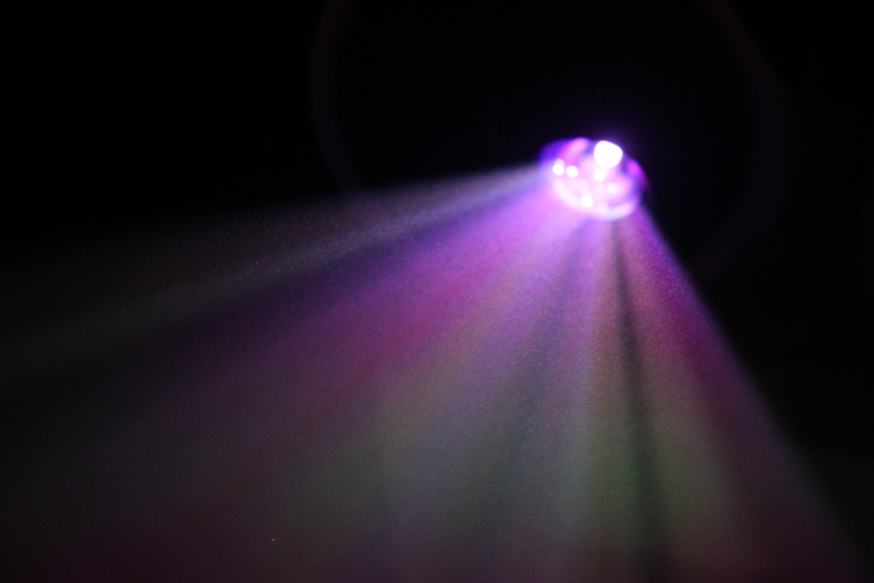 Pink and green projector beam fanning out through haze