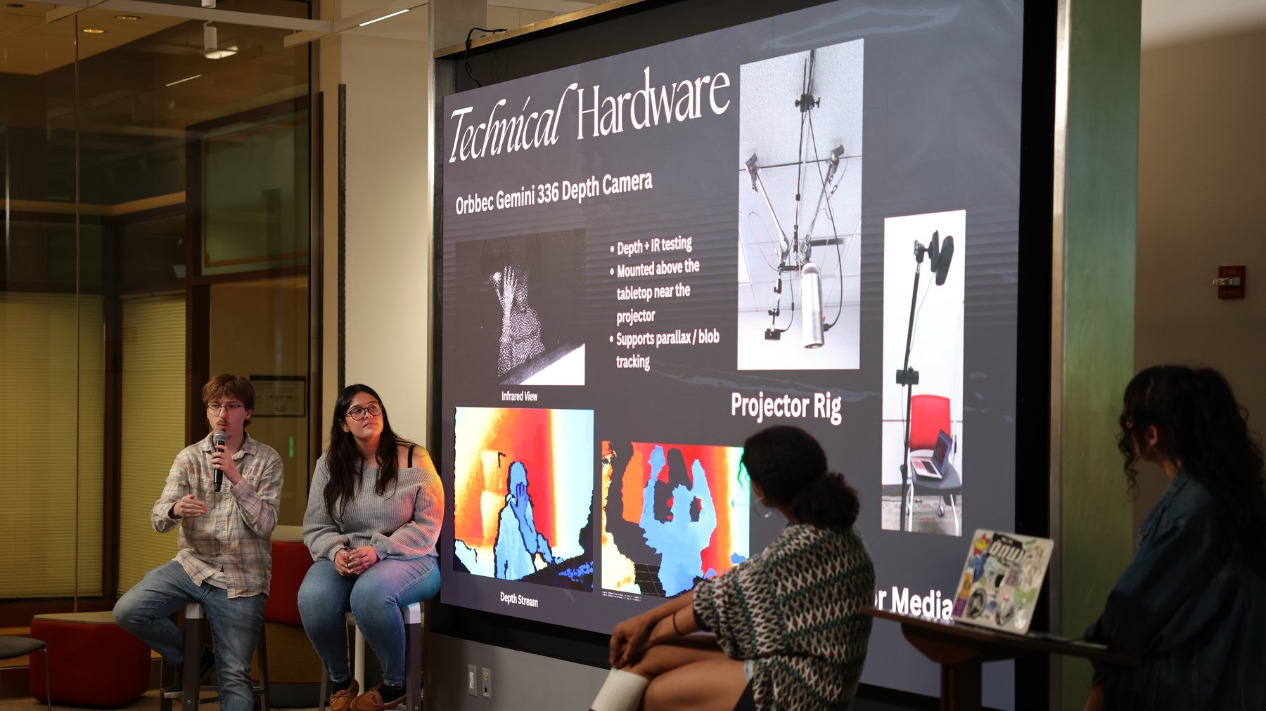Jake speaking into a microphone next to a Technical Hardware slide during the showcase Q&A